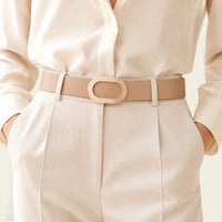 Ceinture La Ceinture Pour Femme beige en cuir avec boucle ovale dorée portée sur un pantalon élégant
