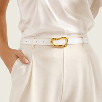 Ceinture La Ceinture Pour Femme blanche en cuir véritable avec boucle métallique dorée organique sur un pantalon beige