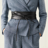 Ceinture à nouer noire La Ceinture Pour Femme Célestine en similicuir avec longs pans sur un tailleur bleu chiné